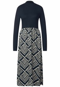 Dlouhá šaty s tmavě modrou horní částí a barevnou krémovou sukní s geometrickými vzory. Měkký materiál, přiléhavý korzet a volná nařasená dolní část.