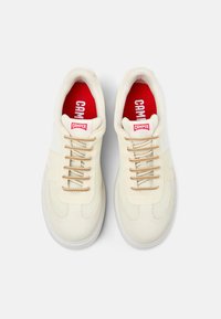 Cream sneakers with mesh and suede panels, beige laces, red insole, and a white sole. Features a prominent "Camper" logo on the tongue.
