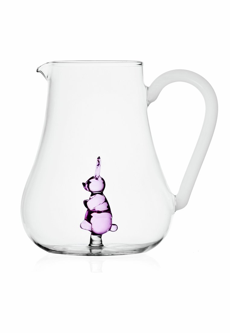 Szklany dzbanek o zakrzywionym kształcie i białym uchwycie, z przezroczystą, fioletową figurką królika w środku. Gładka tekstura i wyraźna widoczność.