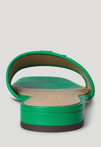 Roheline nahkne liug sandaal siledast tekstuurist, ümarate varvastega ja lame tallaga; omaduse kohta on peene valge aktsent rihma lähedal.