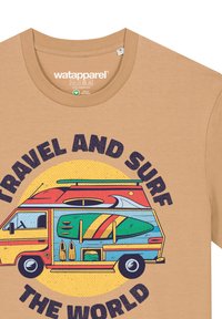Katoenen t-shirt in tan met een kleurrafische afbeelding van een campervan met surfplanken en de tekst "REIS EN SURF DE WERELD" in vet zwart.