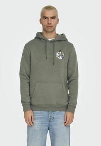 Groene hoodie gemaakt van zachte stof met een trekkoordcapuchon. Bevat een voorkant zak en een geborduurd kleurrijk vlinderontwerp op de borst.