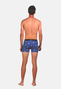 Boxer en bleu marine avec un motif de créatures marines en bleu clair et rouge. Tissu doux, coupe ajustée et taille élastique avec un logo noir.