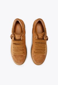 Beżowe zamszowe sneakersy o fakturowanym, bezsznurowym designie, z wełnianym akcentem i złotymi oczkami. Okrągły czubek i gumowa podeszwa.