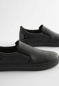 Pantofi negri slip-on cu un superior din piele texturată, o talpă plană din cauciuc și accente elastice pe laterale pentru o îmbrăcare ușoară. Detalii netede negre la toc.