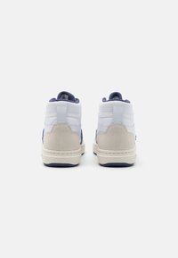Höga sneakers med ovandel i vitt läder, marina blå accenter, en häl i mocka och en krämfärgad gummisula.