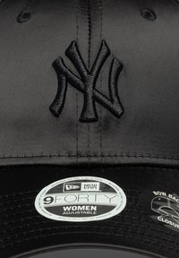 Boné de basebol preto com um logotipo 'NY' bordado. Apresenta um acabamento satinado, faixa ajustável e etiquetas indicando o tamanho e a marca.