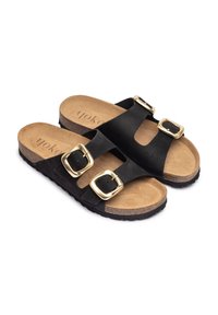 Sandalias de ante negras tipo slide con dos hebillas ajustables doradas, plantilla de corcho y suela de goma negra texturizada. Plantilla interior marrón suave con logo.