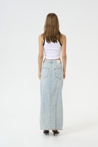 Lys blå denim maksi-skjørt med høy midje, to baklommer og vertikale sømmer. Kombinert med en hvit, kort tank topp.