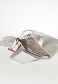 Borsa tote in pelle bianca con chiusura a zip, caratterizzata da un accento rosso, fodera interna con un motivo e una piccola pochette removibile.