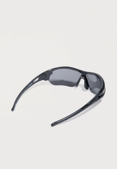 Μαύρα σπορ γυαλιά ηλίου τύπου wraparound με καμπυλωτούς βραχίονες και σκουρόχρωμους φακούς σε λευκό φόντο.