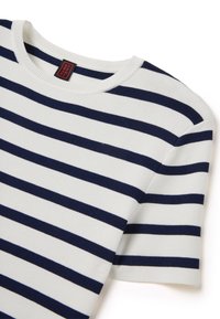 Top corto a maniche corte di colore bianco in maglia con righe orizzontali blu navy, scollatura rotonda e un piccolo cartellino rosso sul colletto. Texture morbida.