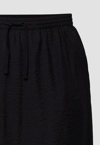 Zwarte rok met een gestructureerde stof, voorzien van een elastische tailleband en een verstelbaar trekkoord. De gekreukte oppervlakte voegt visuele interesse toe.