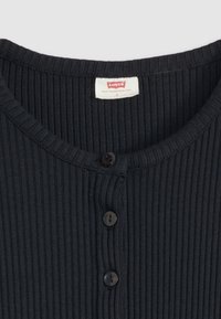 Top de punto negro acanalado con cuello redondo, tres botones y una etiqueta cosida en el cuello. Talla indicada como S.