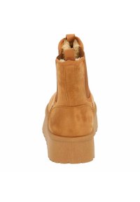 Bottine à cheville en suède marron clair avec une finition texturée, des panneaux latéraux élastiques et une semelle en caoutchouc durable. Doublure en polaire visible en haut.