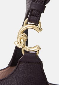 Dark purple leather bag strap featuring a gold-tone clasp with intertwined 'C' design. Textured material with contrasting smooth accents.