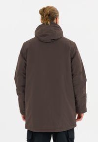 Braune wasserdichte Jacke mit Kapuze, die einen glatten Stoff und einen langen, lockeren Schnitt aufweist. Sie verfügt über subtile Nähte und seitliche Taschen.