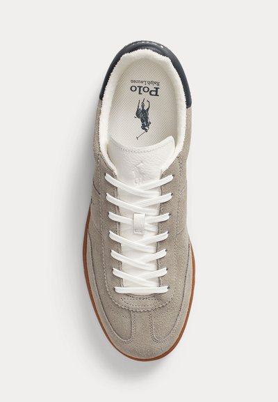 Világosszürke velúr sportcipő fehér bőr nyelvvel, fehér fűzővel, fekete sarokkal, barna talppal és Polo Ralph Lauren logóval belül.