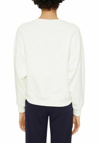 Sudadera blanca con un corte relajado, cuello redondo y hombros caídos. Presenta puños y dobladillo acanalados, fabricada en una suave tela texturizada.