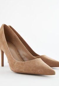 Décolleté in camoscio color cuoio con punta a punta e tacco stiletto sottile, caratterizzate da una fodera interna liscia e una morbida texture.