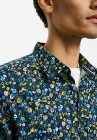 Kurzärmeliges Hemd mit marineblauem Grundton und einem mehrfarbigen Blumenmuster. Hemdkragen mit sichtbaren Knöpfen und Nahtdetails.