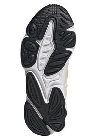 Shoe outsole featuring a mix of black rubber and white material. Textured with various patterns and raised sections for traction.