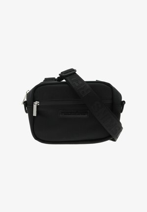 Sac bandoulière noir en tissu texturé avec fermeture éclair, doté d'un patch logo et d'une large sangle réglable. Forme rectangulaire.