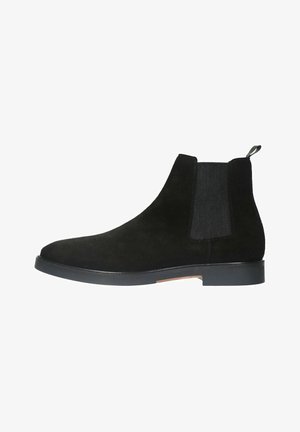 Black suede ankle boot with elastic side panels, a pull tab, rounded toe, and a flat rubber sole. Textured finish complemented by sleek design.