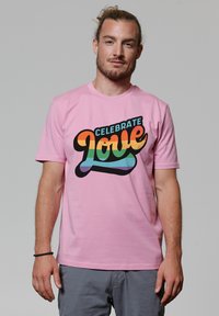 Rosa Baumwoll-T-Shirt mit einem bunten Grafikdesign und dem Text "Feiere die Liebe" in verschiedenen Farbtönen, schwarzem Umriss und lässiger Passform.