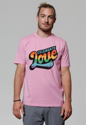 Roze katoenen T-shirt met een kleurrafische afbeelding met de tekst "Vier de Liefde" in verschillende tinten, zwarte rand en casual pasvorm.