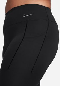 Sorte leggings med høy midje, laget av elastisk stoff. Har en liten sølvfarget Nike-logo og flat sømmer for komfort.