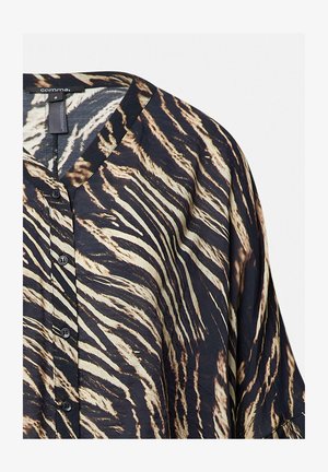 Blusa in stampa animale nero e crema con scollatura a V, chiusura a bottoni e vestibilità ampia, caratterizzata da una superficie liscia e un tessuto fluido.