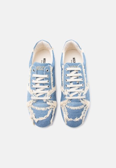 Paire de baskets en denim bleu avec bords effilochés et lacets blancs, vue de dessus sur un fond blanc uni.