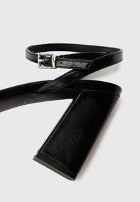 Melnas augstpapēžu sandales no teksturētas ādas, ar plānu potītes siksnu ar sudraba sprādzi un masīvu papēža dizainu.