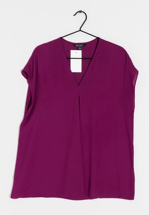 Lilla bluse med korte ærmer og V-udskæring, lavet af letvægtsstof. Har en afslappet pasform og lige kant nederst. Inkluderer et mærke med mærkenavn.