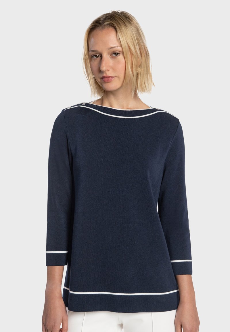 Haut en maille bleu marine avec manches trois-quarts, rayures blanches d'accentuation au niveau de l'encolure et de l'ourlet, et coupe décontractée.