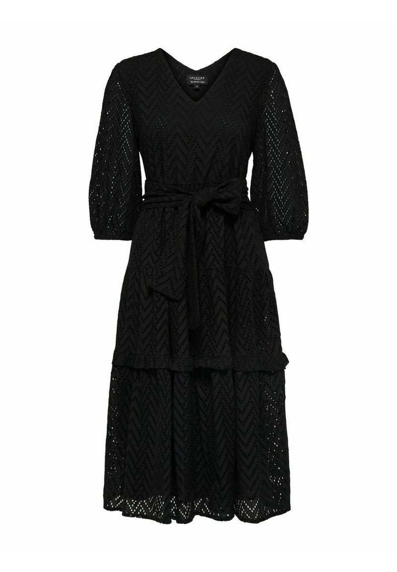 Svart spetsklänning med V-ringning, trekvartsärmar och en midja med bälte. Har en lagrad kjol med ett chevronmönster.