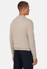 Svetlobežový pulóver, rebrovaná textúra, okrúhly výstrih, priliehavé manžety a lem; skombinovaný s námorníckymi nohavicami; minimalistický dizajn.