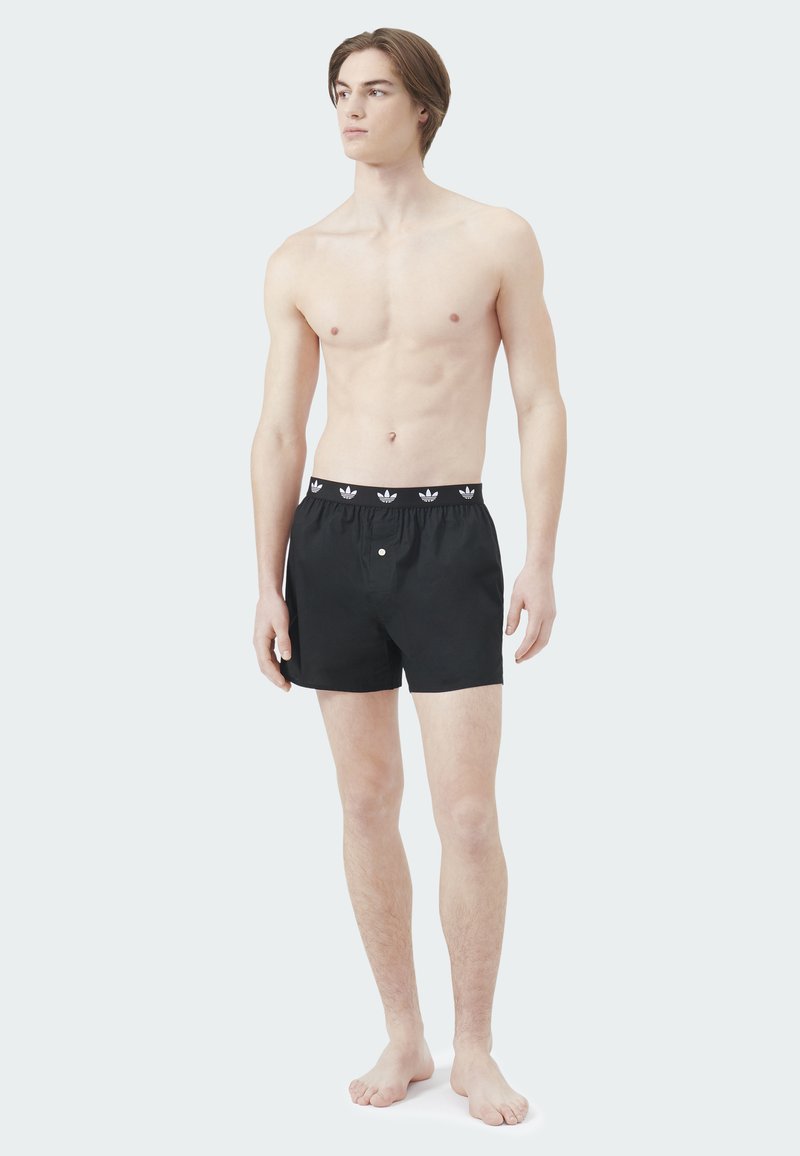 Schwarze Boxershorts mit elastischem Bund und weißen Logoakzenten, für eine lockere Passform entworfen und aus weichem Stoff gefertigt.