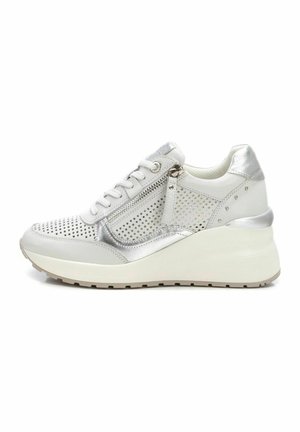 Zapatilla blanca y plateada con diseño perforado, cordones en la parte frontal, cremallera lateral y tacón cuña. Presenta un exterior sintético y suela de goma.