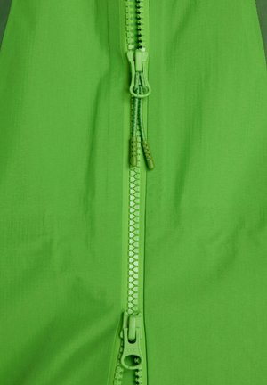 Tessuto verde con una texture liscia, caratterizzato da una cerniera centrale dello stesso colore. La ferramenta include una zip YKK e due cursori.