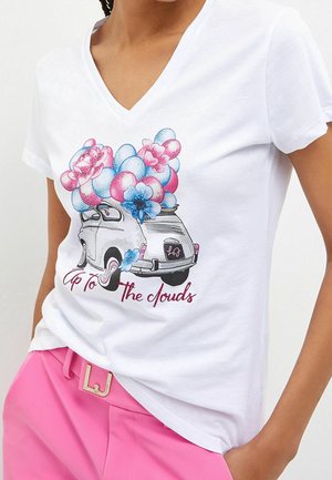 Biała bawełniana koszulka z dekoltem w kształcie litery V, ozdobiona kolorową grafiką przedstawiającą zabytkowy samochód przyozdobiony różowymi i niebieskimi kwiatami oraz balonami.