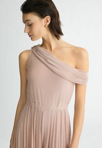 Één-schouder, blush roze jurk met een gedrapeerde halslijn en een gathered taille. Gemaakt van een zachte, textuurstof met een lichte glans.