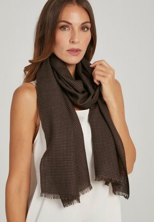 Bruine sjaal met hondentandpatroon, gemaakt van een gestructureerde stof, met franjeranden en losjes om de nek gewikkeld.