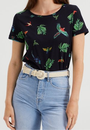 Granatowy t-shirt z krótkim rękawem z tropikalnym nadrukiem ptaków i liści, okrągły dekolt, miękka tkanina. Połączony z jasnoniebieskimi dżinsami z wysokim stanem i plecionym paskiem.