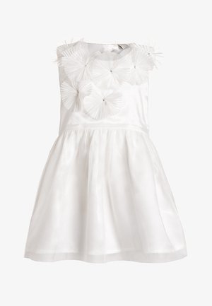 Robe blanche sans manches avec corsage ajusté, jupe évasée et appliques florales en tulle superposées décoratives sur le haut de la poitrine et les épaules.