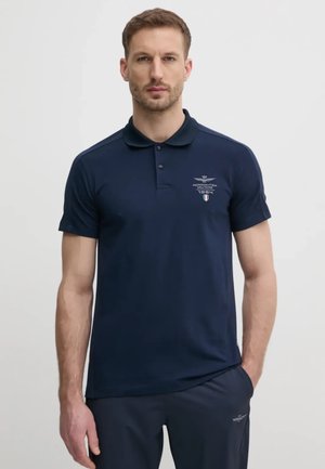 Polo shirt blu navy con colletto classico, maniche corte e dettagli del logo ricamati. Realizzato in un tessuto morbido, presenta una vestibilità slim.