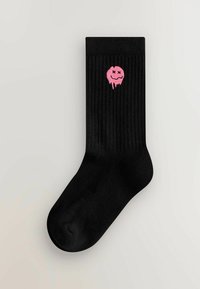 Sorte ribbede sokker med et pink dryppende smiley ansigt design foran. Glat tekstur med en standard sokkeform.