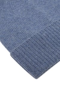 Miękka, niebieska, wełniana czapka beanie z prążkowanym mankietem, szczegółowe zbliżenie ukazujące teksturę i wzór ściegów na białym tle.