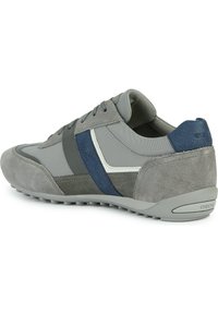 Zapato deportivo gris que combina materiales de ante y malla, con detalles en azul y blanco, y una suela de goma texturizada con puntera redonda.